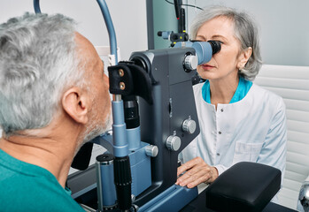 Senior man getting eye exam at ophthalmology clinic with optometrist. Ophthalmology for older people