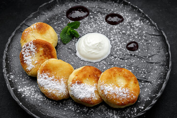 Cottage cheese cheesecakes on a black plate plate