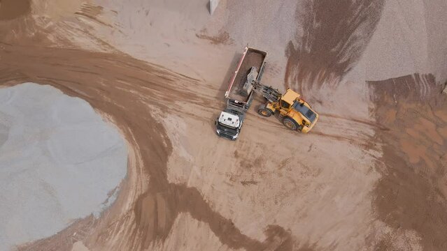 Excavator bucket loads soil into the back of large truck, Sand mining in quarry, Industrial sand extraction for construction industry