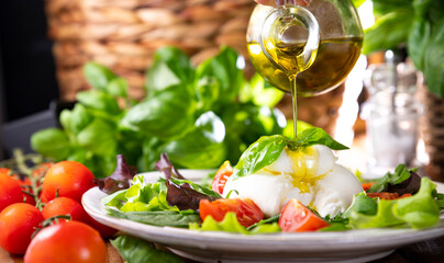 Salad with Tomatoes, Burrata, basil,olive oil. middle name Burratina. Traditional cheese from the south of Italy in the Puglia region. Round soft cheese inside liquid stracciatella texture