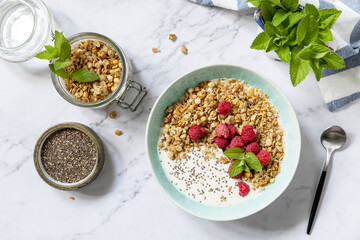 Breakfast, sweet dessert. Diet nutrition concept. Homemade granola with yogurt, chia seeds and raspberry on a marble tabletop. View from above.