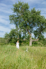 Beautiful girl in a white dress with flowers in a field overlooking the sky