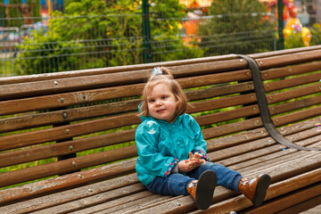 portrait of a little girl in the park on a bench catches soap bubbles