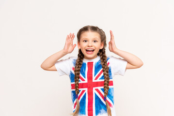 English language courses. A little girl with a big smile with the flag of Great Britain on an isolated white background.