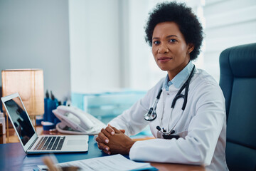 Black female general practitioner working at doctor's office and looking at camera.