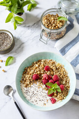 Breakfast, sweet dessert. Diet nutrition concept. Homemade granola with yogurt, chia seeds and raspberry on a marble tabletop.