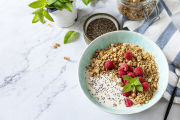 Breakfast, sweet dessert. Diet nutrition concept. Homemade granola with yogurt, chia seeds and raspberry on a marble tabletop. Copy space.