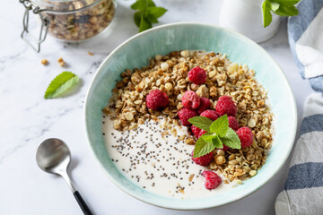 Fototapeta na wymiar Breakfast, sweet dessert. Diet nutrition concept. Homemade granola with yogurt, chia seeds and raspberry on a marble tabletop.