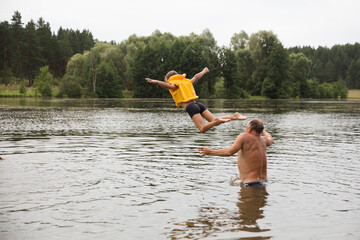 Family on vacation splashing in a lake. Kid boy jumping in outdoor in a lake. Happy grandparents...