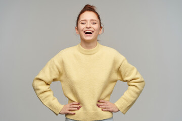 indoor studio portrait of young ginger female with freckles posing over grey background laugh and looking into camera