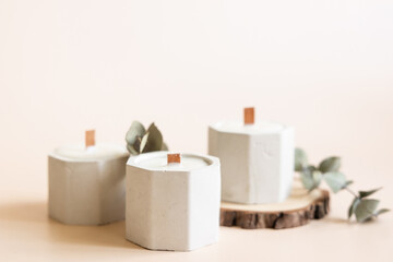 Handmade candles from paraffin and soy wax in concrete plaster candlestick with wooden wick and dry herbal isolated on pastel beige background. Copy space