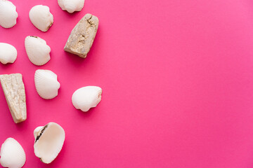 Obraz premium Top view of seashells and stones on pink background.