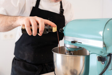 A man baker cooking a red velvet cake at home, preparing the cake by adding vanilla cuttlefish in the food processor, work at home
