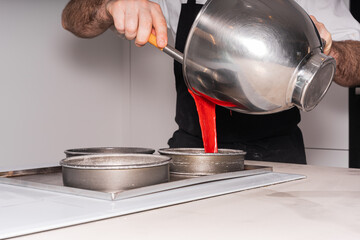 Hands of a man cooking a red velvet cake at home, adding the sponge cake in the molds, work at home