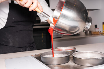 Hands of a man cooking a red velvet cake at home, adding the sponge cake in the molds, work at home