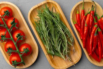 Fresh tomatoes, rosemary and chili peppers on gray background