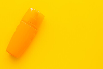 Top view of bottle of sunblock on yellow surface.