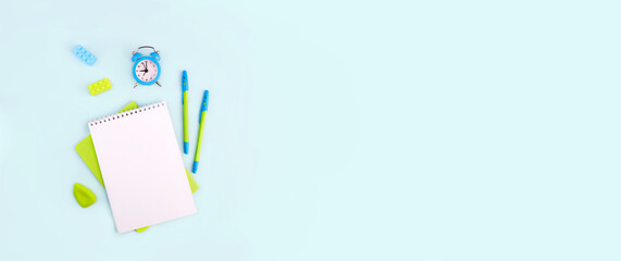 Banner. Back to school. School supplies on light blue background. Notebook, pens, alarm clock and rubber bands. Flat lay, copy space. 