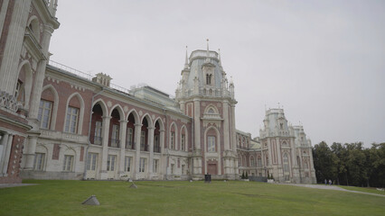 Obraz premium Palace and Park ensemble in Tsaritsyno, Russia. Action. Facade of the Grand Palace, beautiful historic building and green grass on cloudy sky background.