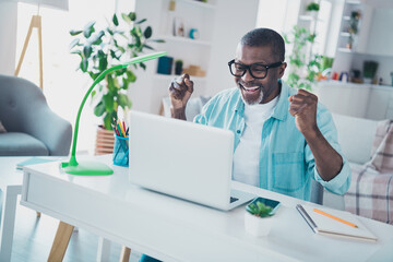 Photo of excited middle aged man financier sit table celebrate partnership agreement fist up in...