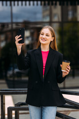 Portrait of sbusiness woman hold the paper cup and take selfie in the city.