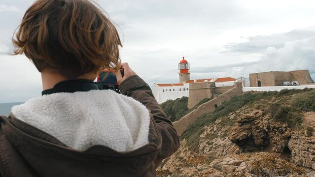 Child tourist taking pictures of Cape St. Vincent Lighthouse, Portugal