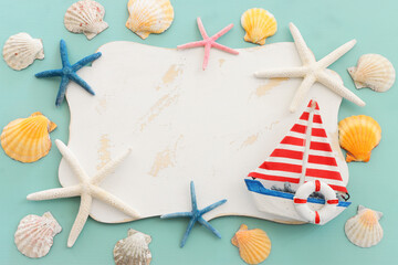 nautical concept with sail boat, seashells, star fish and blank board for copy space over mint blue...
