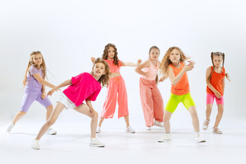 Happy, sportive little girls, kids in bright colorful clothes dancing modern dance isolated on...