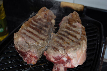 two sirloin steaks being grilled on iron cast