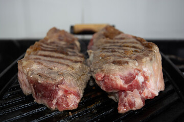 two sirloin steaks being grilled on iron cast