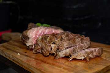 rare sirloin steak grilled, on wooden cutting board and black surface