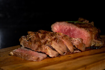 rare sirloin steak grilled, on wooden cutting board and black surface