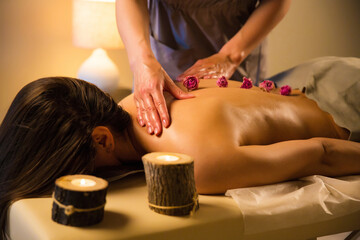 relaxing massage for woman by candlelight and flowers. massage with weak warm light