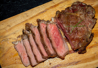 rare sirloin steak grilled, on wooden cutting board and black surface