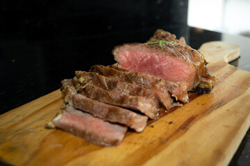 rare sirloin steak grilled, on wooden cutting board and black surface