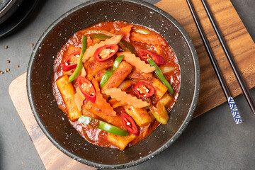 Close-up of tteok-bokki on wood tray, stir-fried rice cake is a popular Korean food. Spicy soup with added gochujang. Sprinkle with roasted sesame seeds.