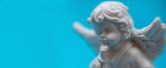 Little beautiful guardian angel on blue background. Copy space.