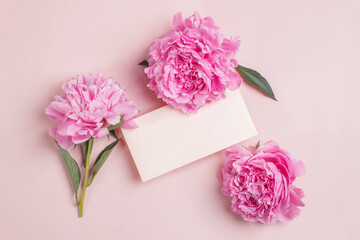 Fototapeta na wymiar Invitation or greeting card mockup with envelope and delicate pink peonies on pastel pink background