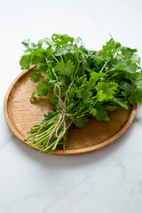 Fresh cilantro bunch on wooden plate organic herbs