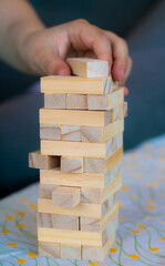 Jenga game playing. Kid hand putting wooden bricks. Closeup. Family fun, entertainment and board games concept