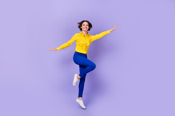 Fototapeta na wymiar Full size photo of impressed young brunette lady jump wear shirt pants shoes isolated on purple background