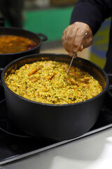 Guiso de arroz con gambas en cazuela y el chef removiendo con cuchara