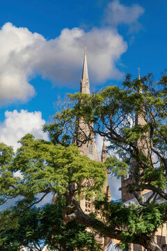 Church. Simple religious building behind green trees under blue white cloudy sky, Sydney Australia