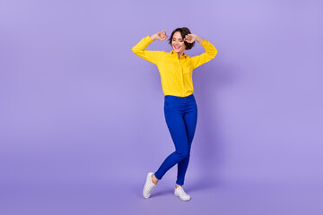 Fototapeta na wymiar Full size photo of cool millennial brunette lady dance wear shirt trousers sneakers isolated on purple background