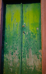 old weathered green wooden doors paint peeling and fading exterior doors of old house in the Azores of Portugal on the island of faial vertical format background or backdrop room for type content 