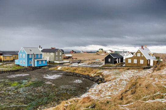 Flatey, Iceland, May 5, 2022: the dark clouds of a recent snow storm still loom over the village while snow is melting on the fields
