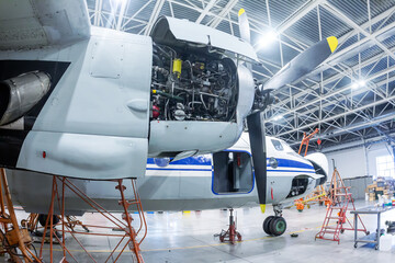 Transport turboprop aircraft in the hangar. Close-up of an open airplane engine. Checking mechanical systems for flight operations