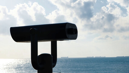Binoculars on observation deck on background of sea. Concept. Black modern binoculars for viewing territory on coast. Tourist entertainment in form of binoculars by sea on sunny day