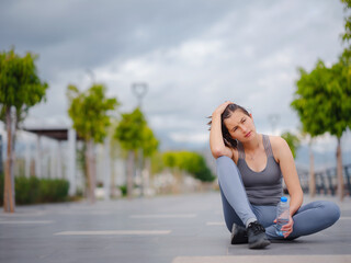 outdoor sports, workout and wellness concept. asian young strong, confident woman in sportive clothes Relaxing After Fitness Workout In Park. Female runner taking break from running sport.