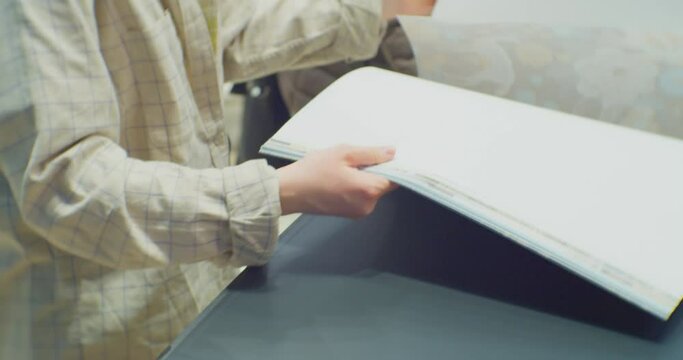 the engineer flips through a large catalog lying on the table.unrecognizable businesswoman at workplace close up